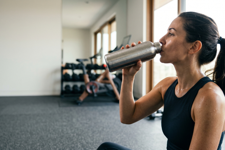 woman drinking water at gym