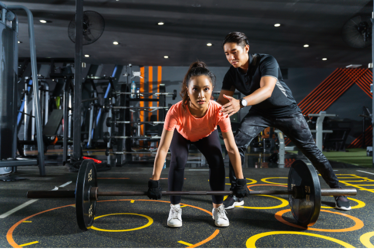 woman being trained at gym by trainer